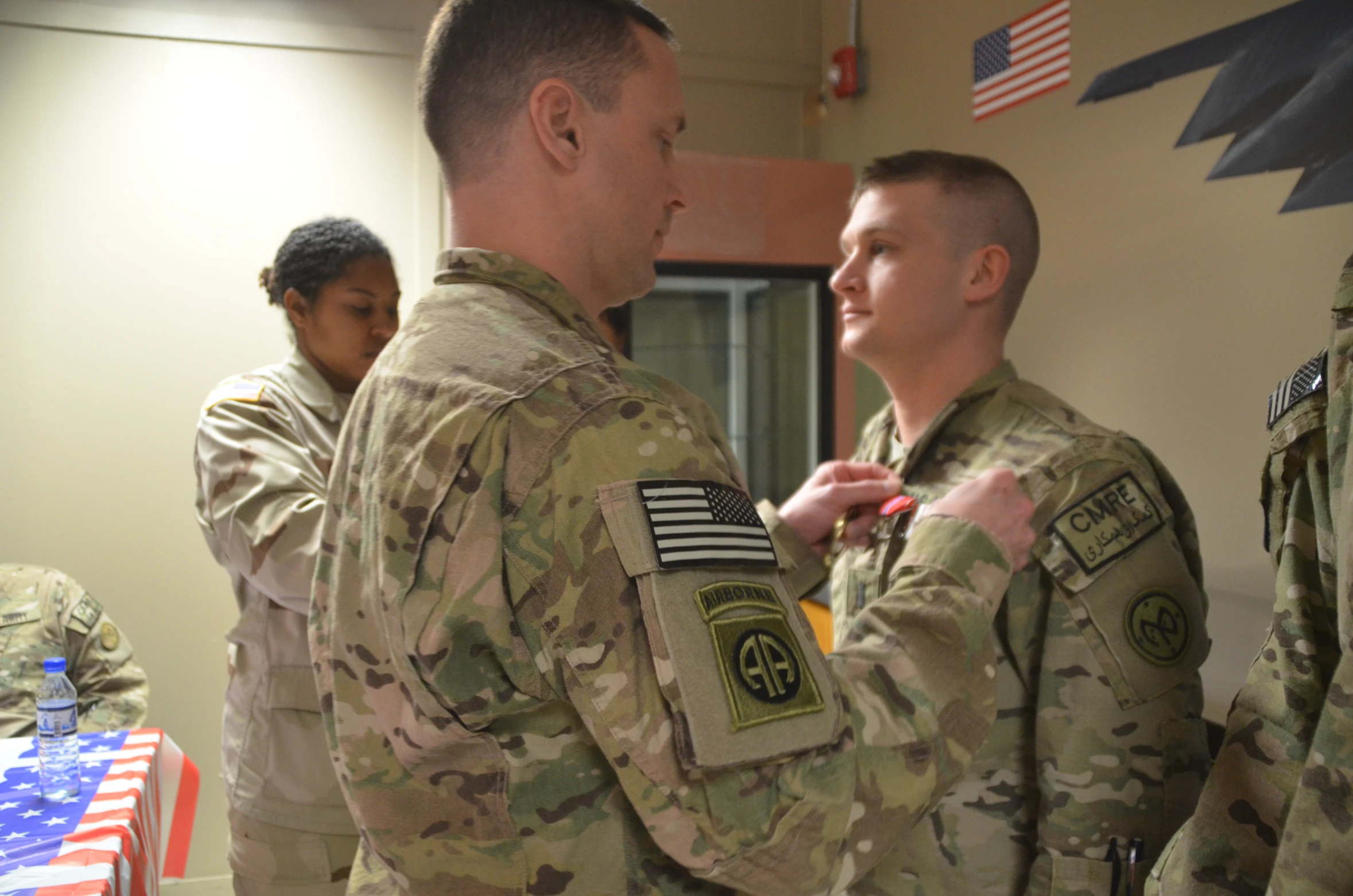 men in military uniforms helping each other get ready to put on the flag