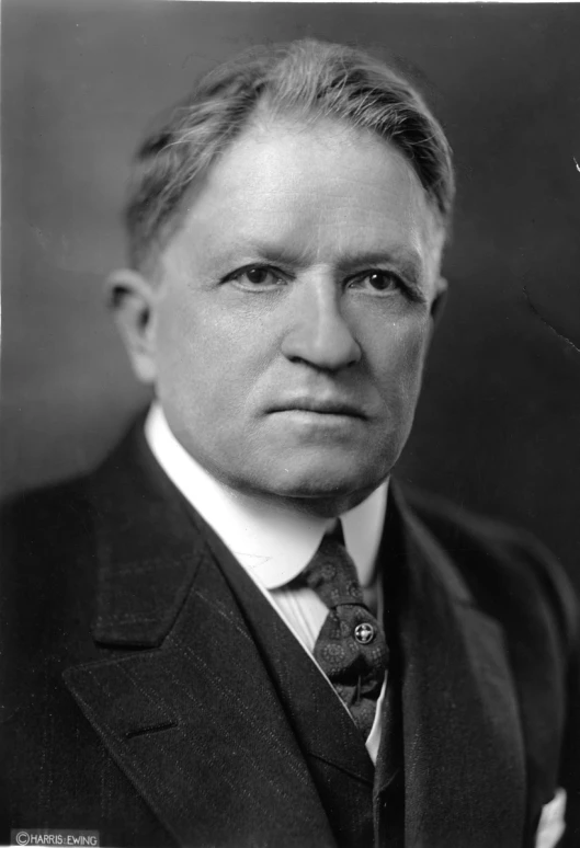 a man with a white shirt and suit looks away from the camera