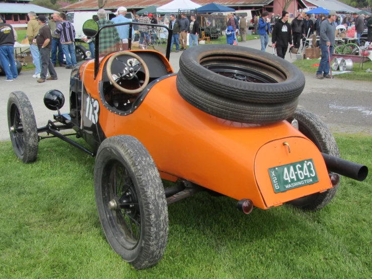 a orange sports car with two tires is parked on the grass