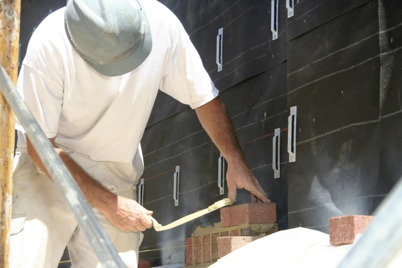 a man in white shirt working on building with bricks