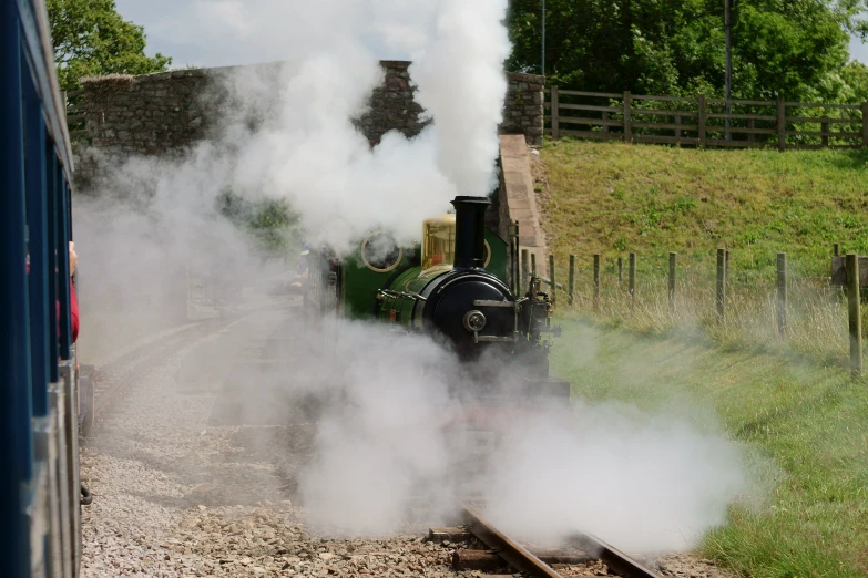 steam coming out of a train as it moves down the tracks