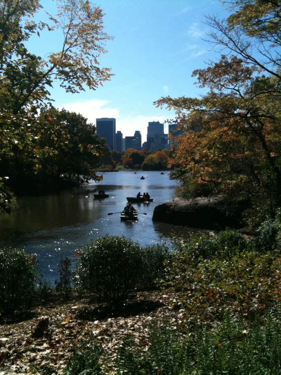 several small boats on a river with tall buildings in the background