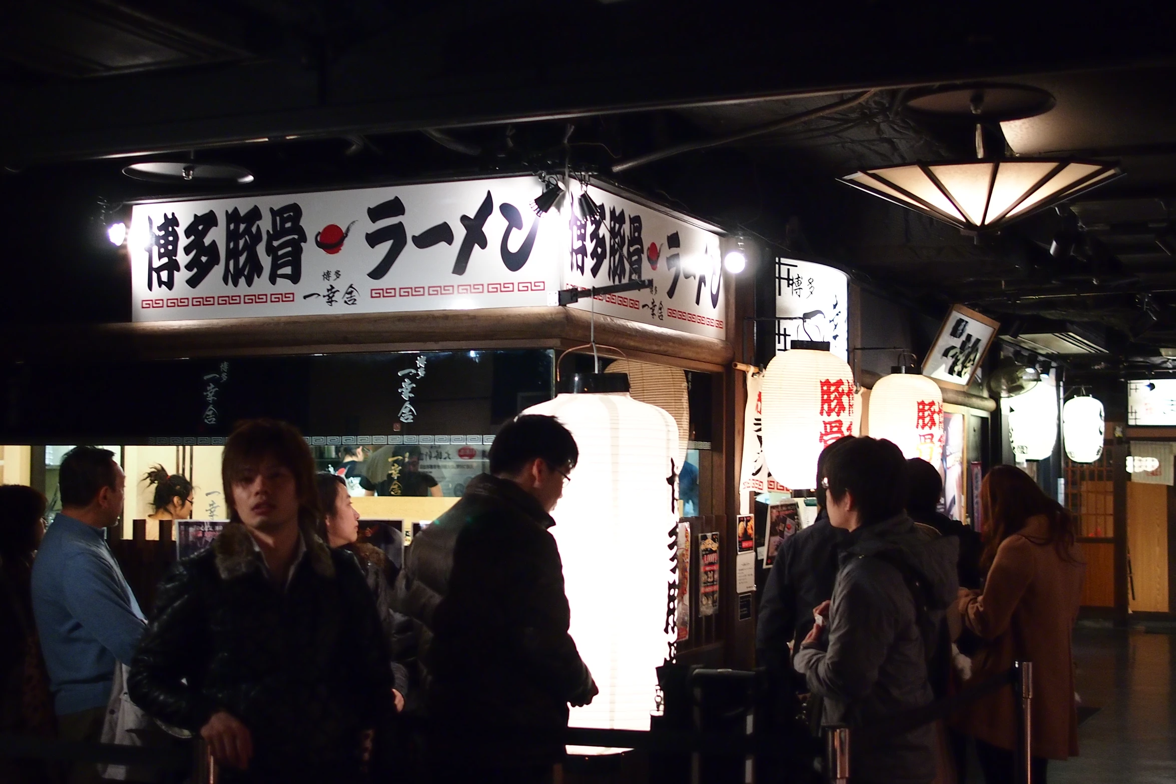 people standing outside of an asian restaurant with people on either side of it