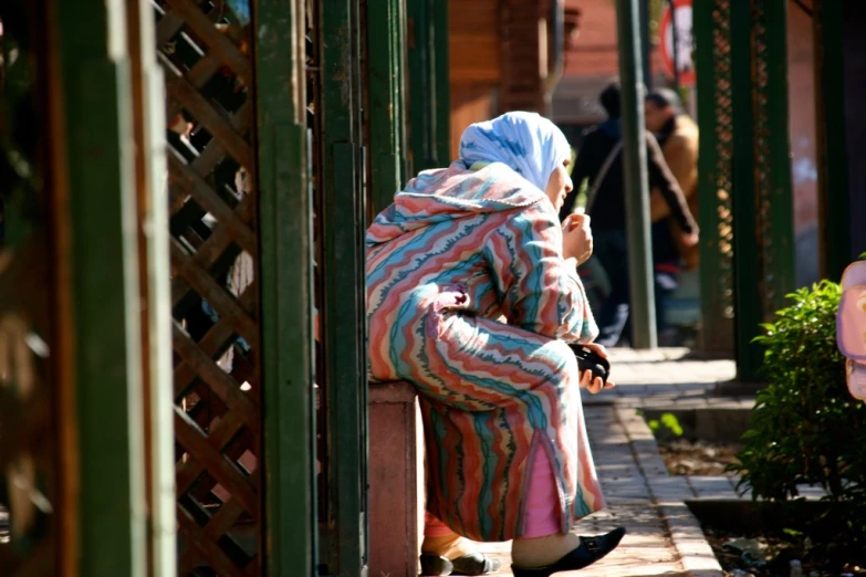 a woman sits on the street smoking a cigarette