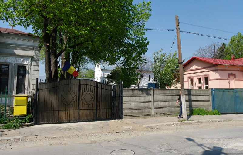 an old fence on the side of the road with a house in the background