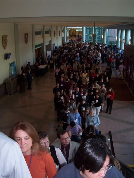 a large group of people stand around in an office building