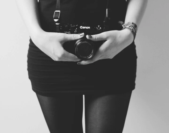 woman holding an electronic camera while posing for the camera