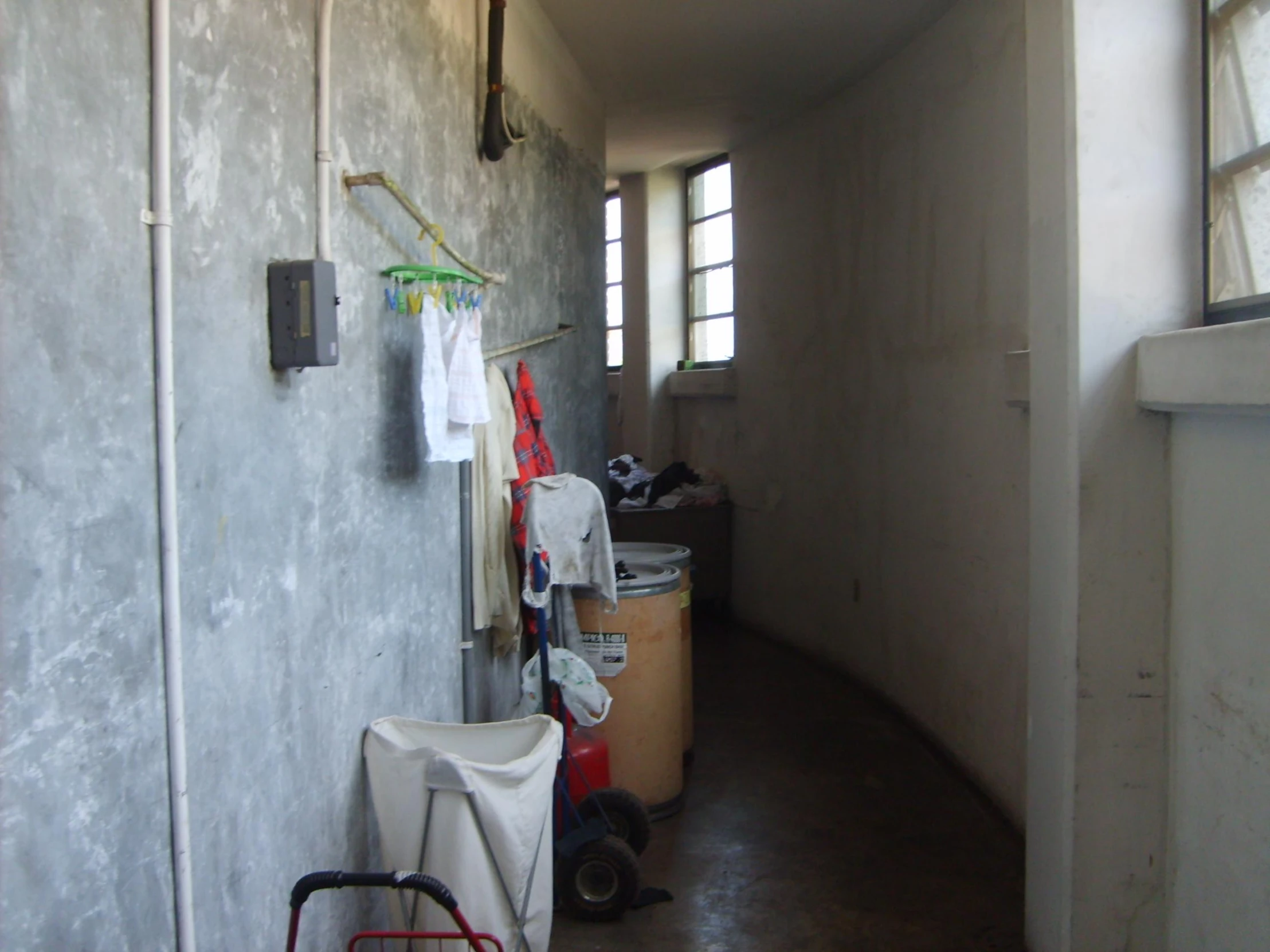 a narrow hallway has several trash cans along the wall