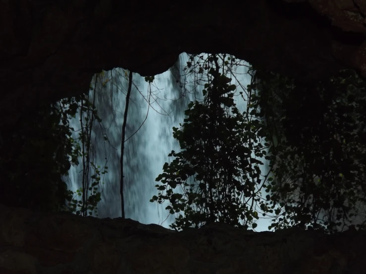 a large waterfall seen from behind an opening in the rocks