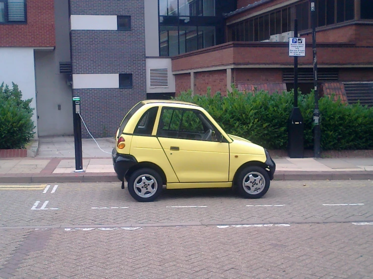 small electric car with bright yellow paint on it at an intersection