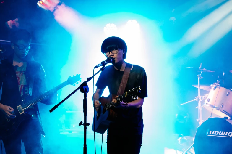 a man standing in front of a microphone and guitar on stage