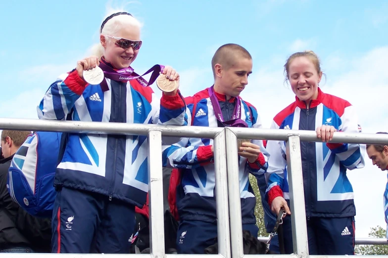 four people wearing blue and red outfits are standing behind a fence