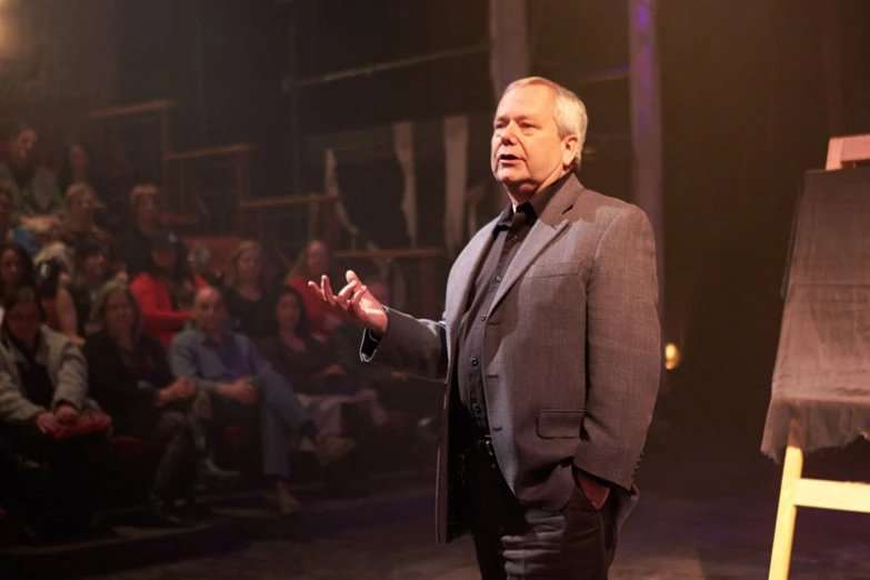 the old man is presenting a presentation in front of an audience