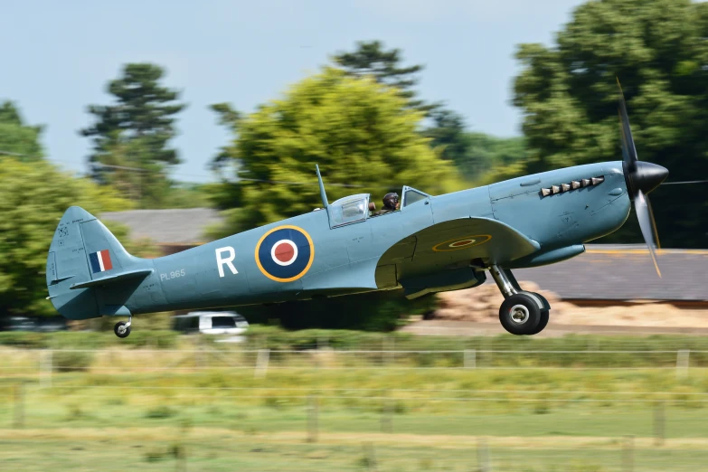 an old green plane is taking off into the air