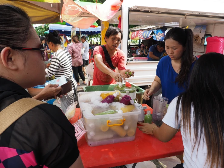 people gathered around a table with many containers