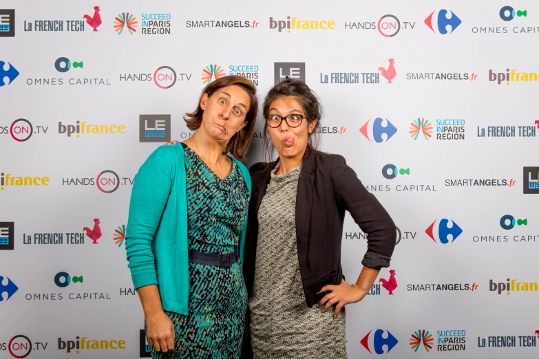 two women in front of a poster on a red carpet