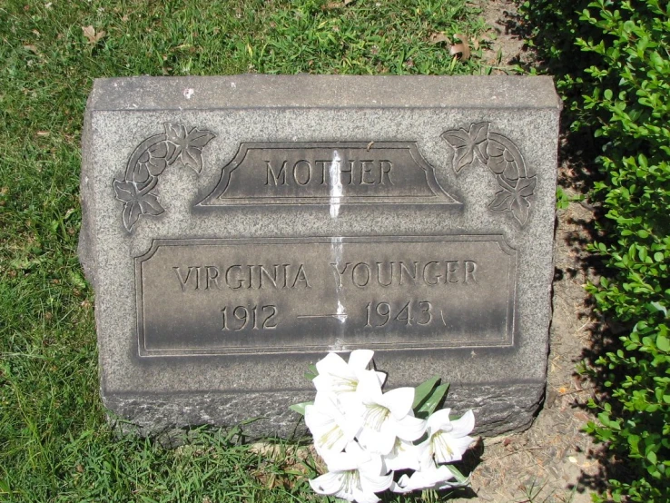 a grave marker and flower in a yard