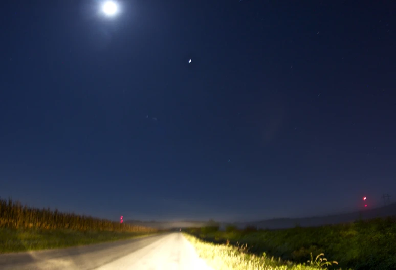 an empty road at night with the moon