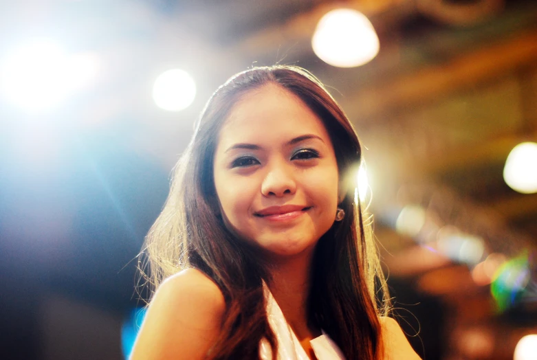 a girl sitting in front of a light with her hand on her hip