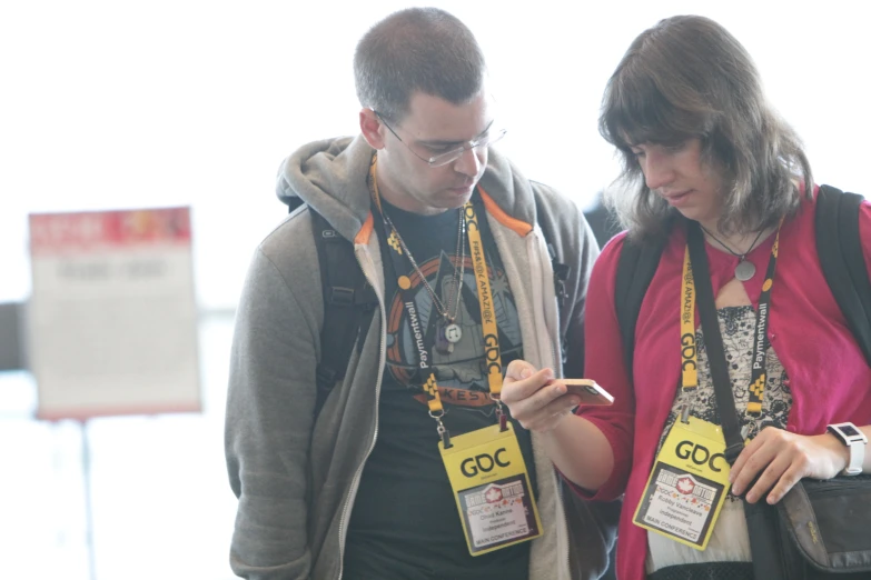 two people looking at their cell phones and holding their bags