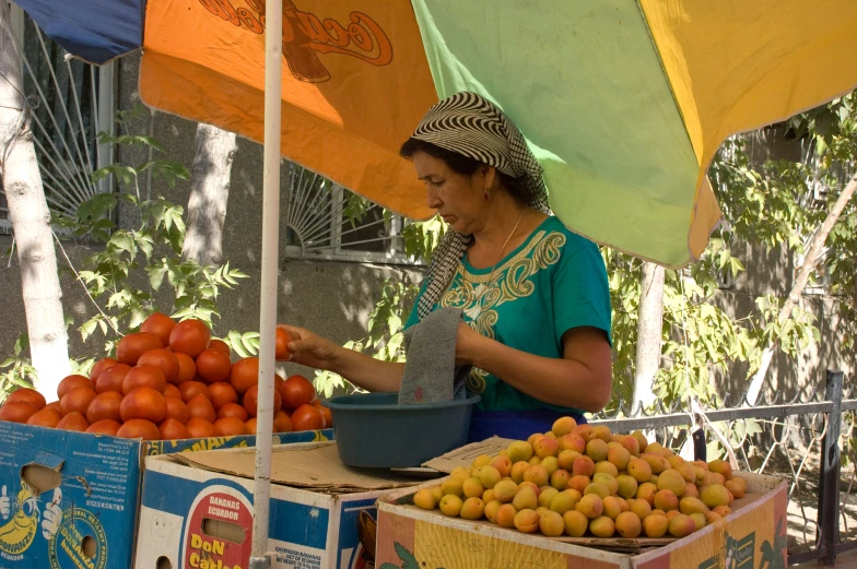 a woman standing under a colorful umbrella at an outdoor fruit stand