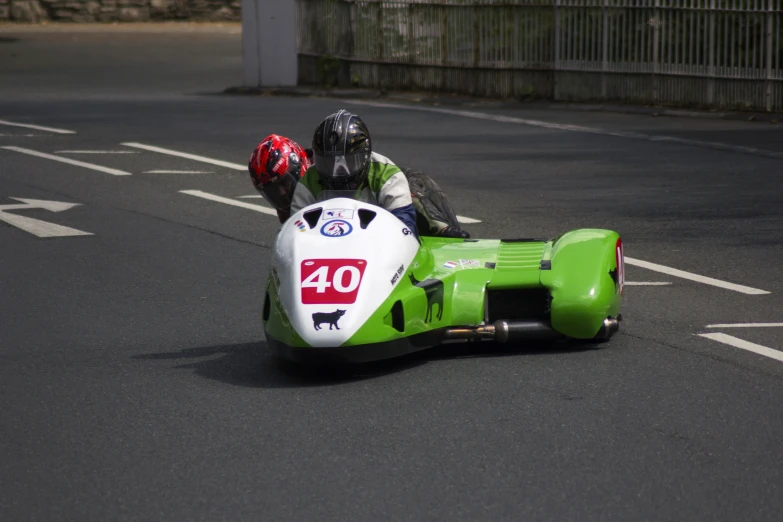 two men riding on a small race car