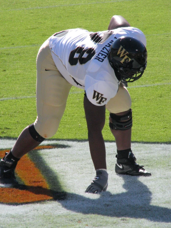 a man in uniform standing on a field with his hand over his knees