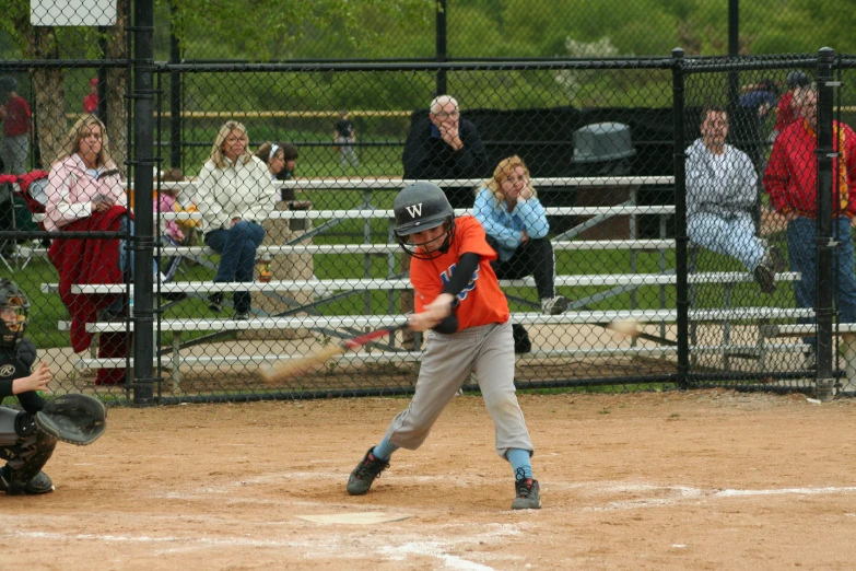 children playing baseball on a field with spectators watching