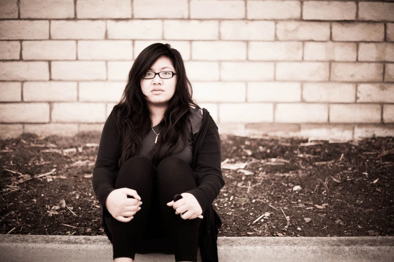 a woman sitting on the ground wearing glasses