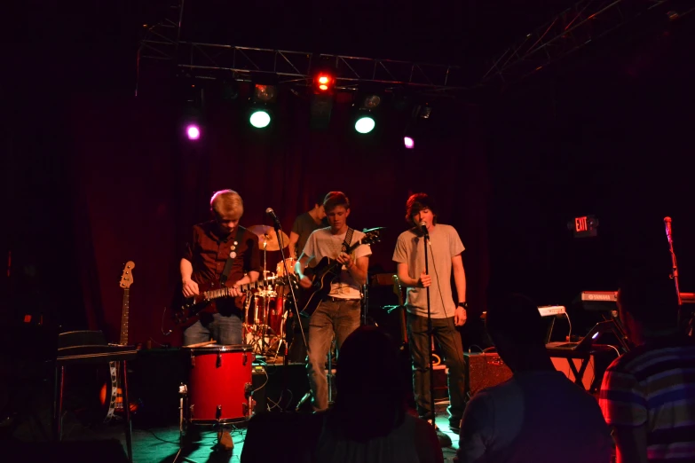 three men standing on a stage playing guitars