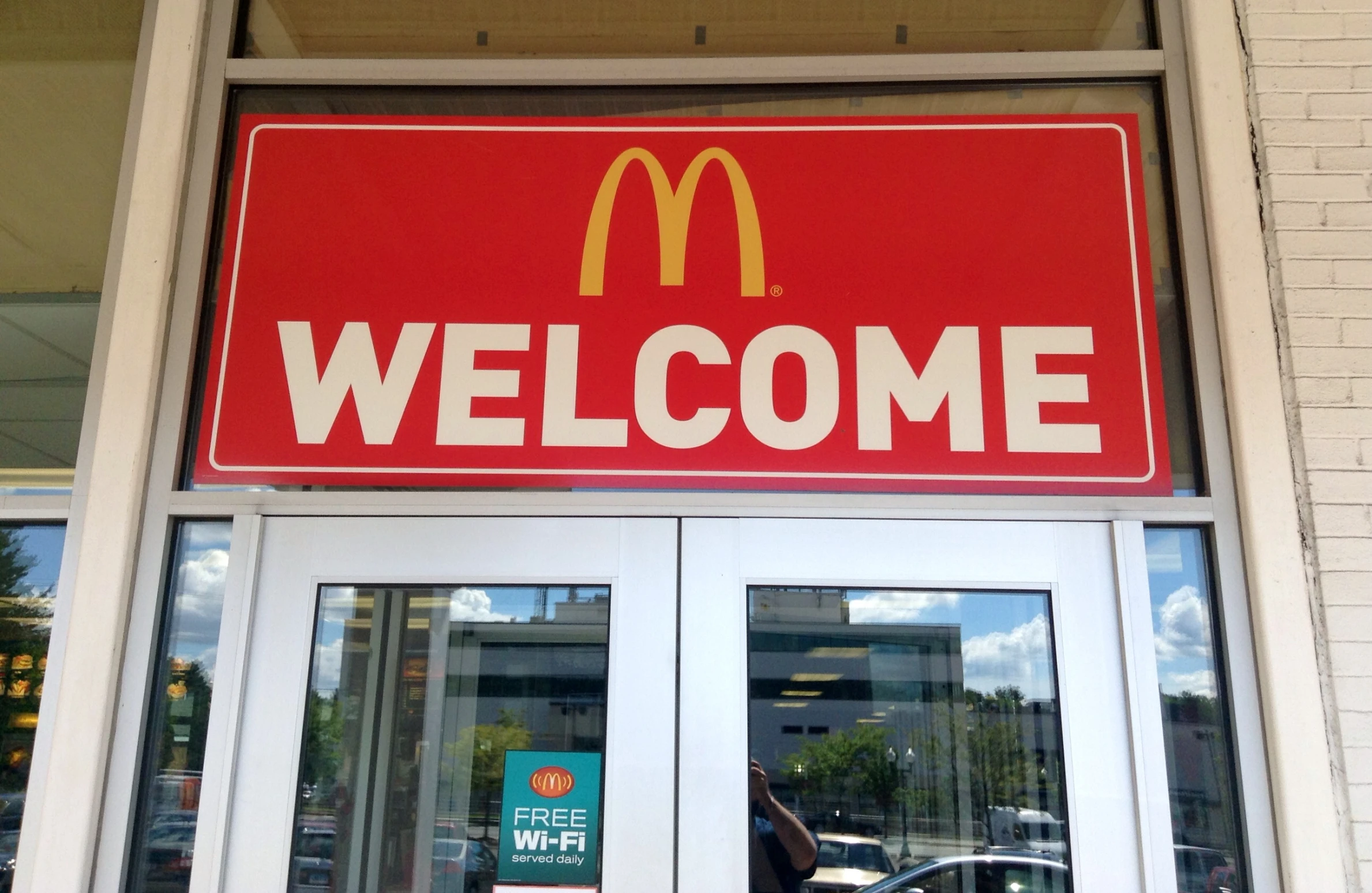 a welcome sign is hanging from the front door of a mcdonald's restaurant