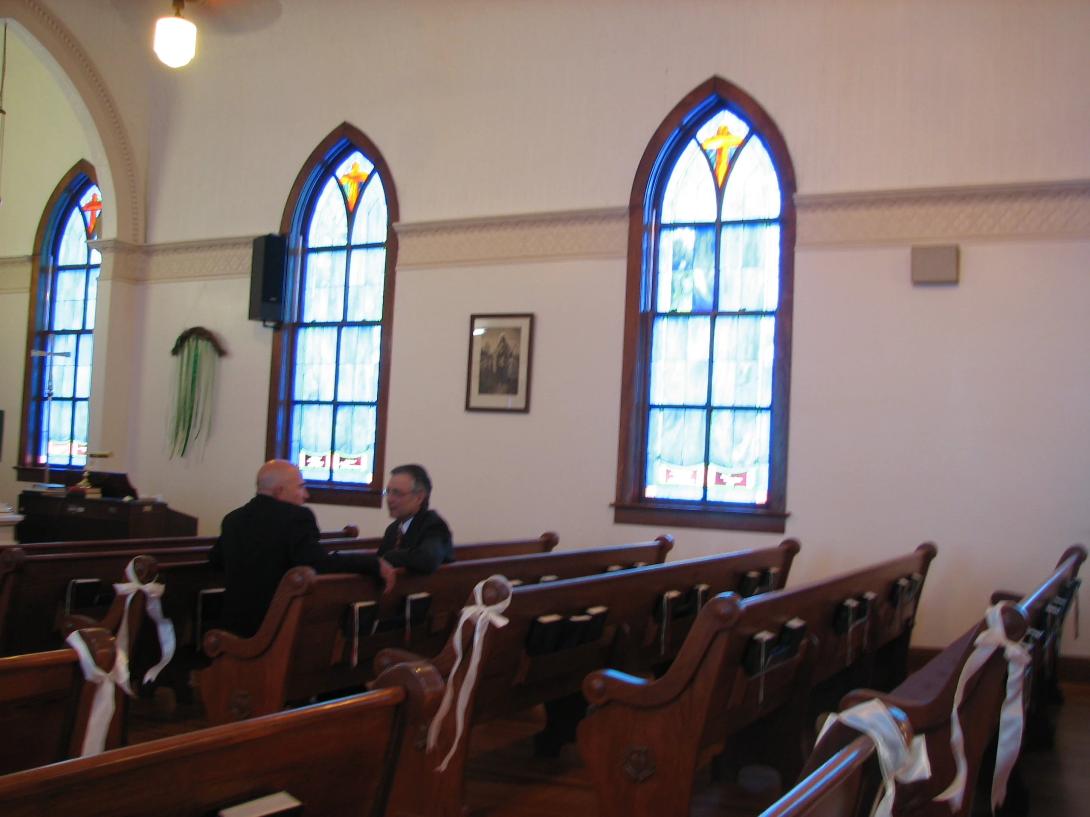 two people sitting at pews in front of stained glass windows