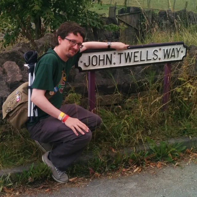 man leaning on the side of road next to a road sign