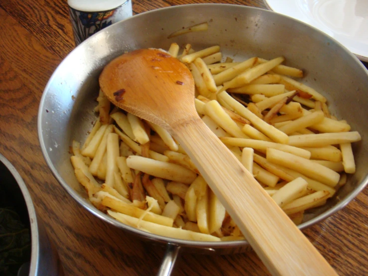 wooden spoon in a wok with french fries