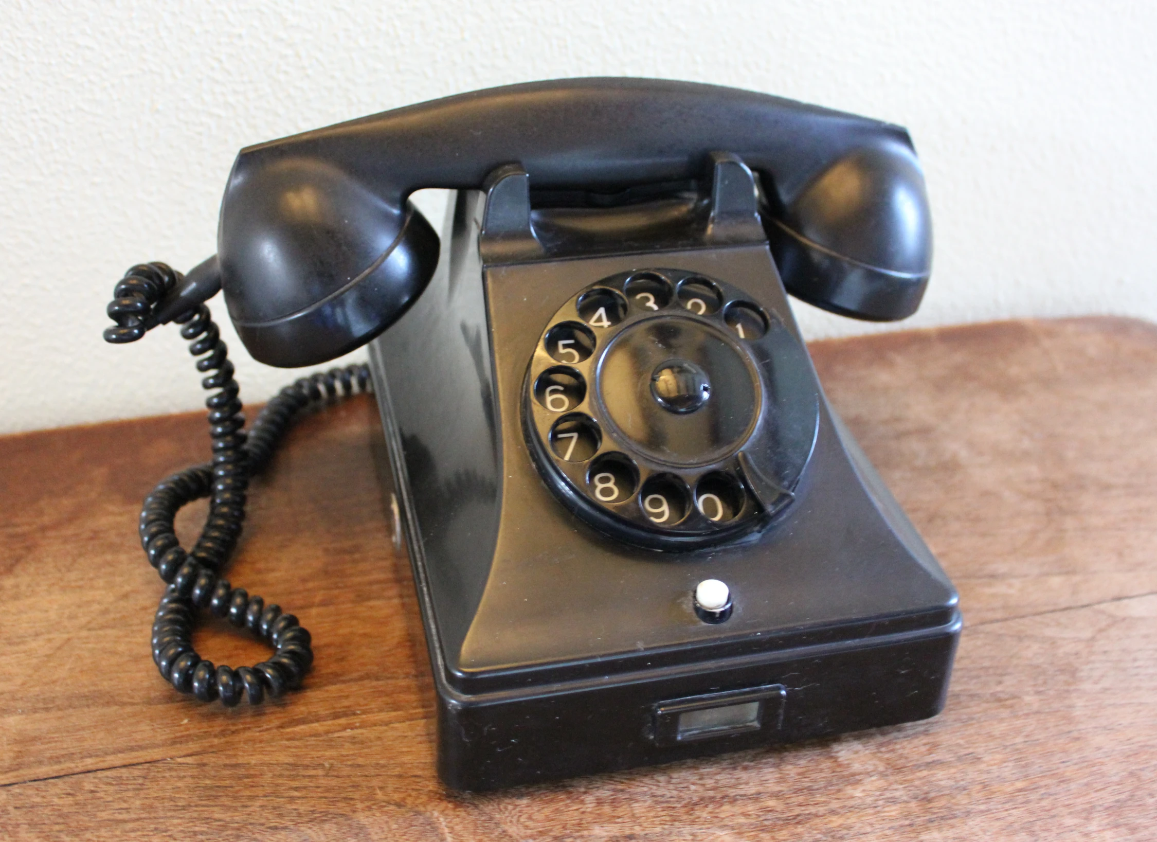 an old style telephone sits on a wooden desk