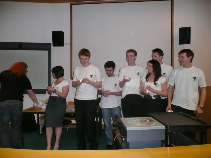 five people holding up white controllers as two of them stand beside each other with two of the men holding the controllers