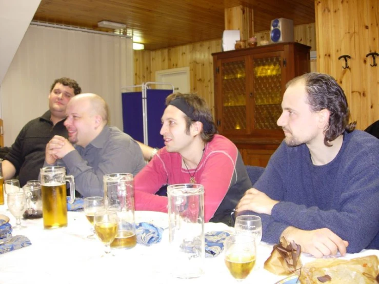 men sitting around a table with beers in their hands