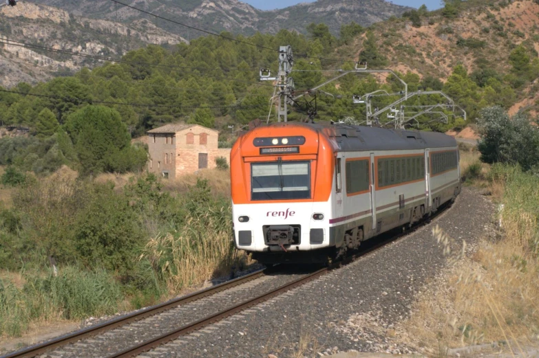 an orange train traveling down the tracks near buildings