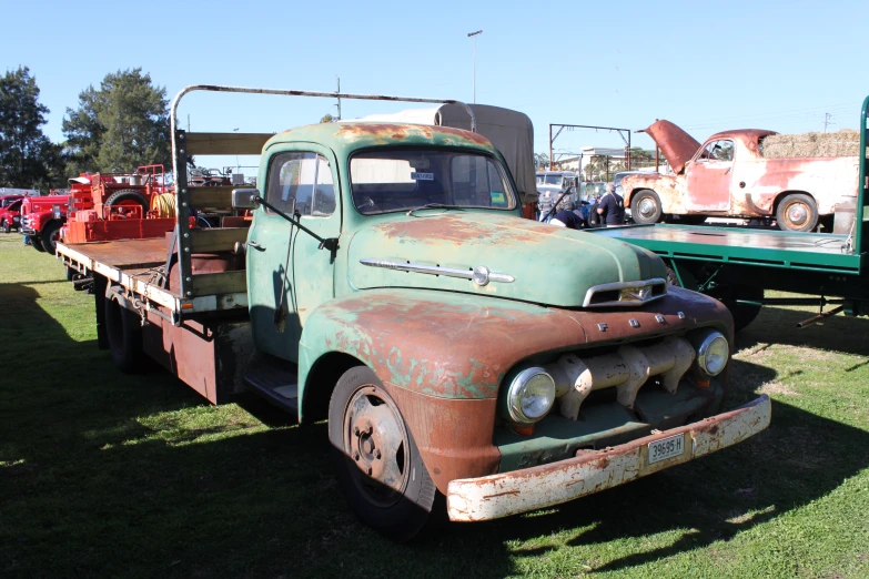 an old rusty green truck parked in the grass