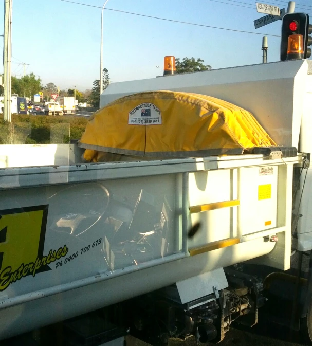 a white truck with a yellow tarp covering the back