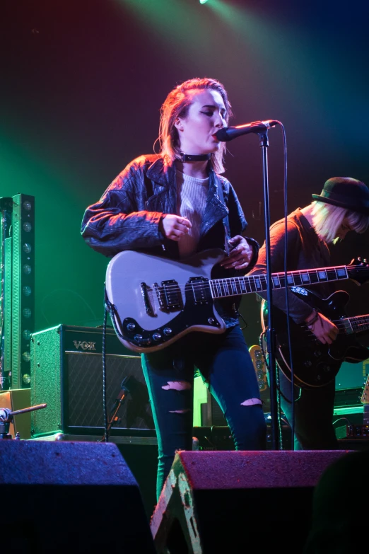 a woman is playing guitar on stage with an adult male