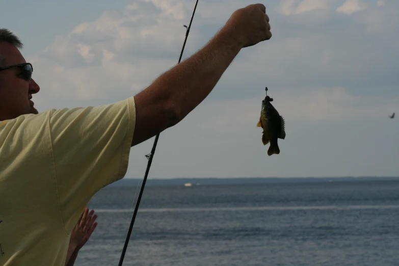 man holding onto fishing rod with small fish hanging in it