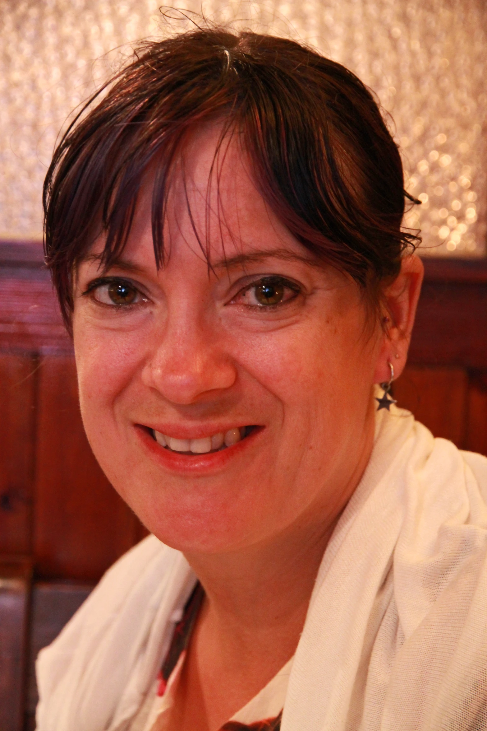 a woman sitting next to a brown wall smiling