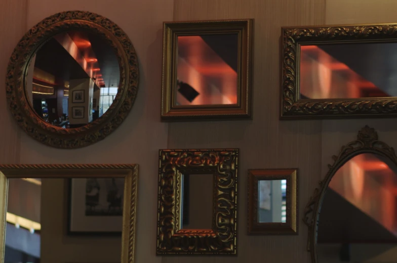 a variety of wall mounted mirrors and framed pographs