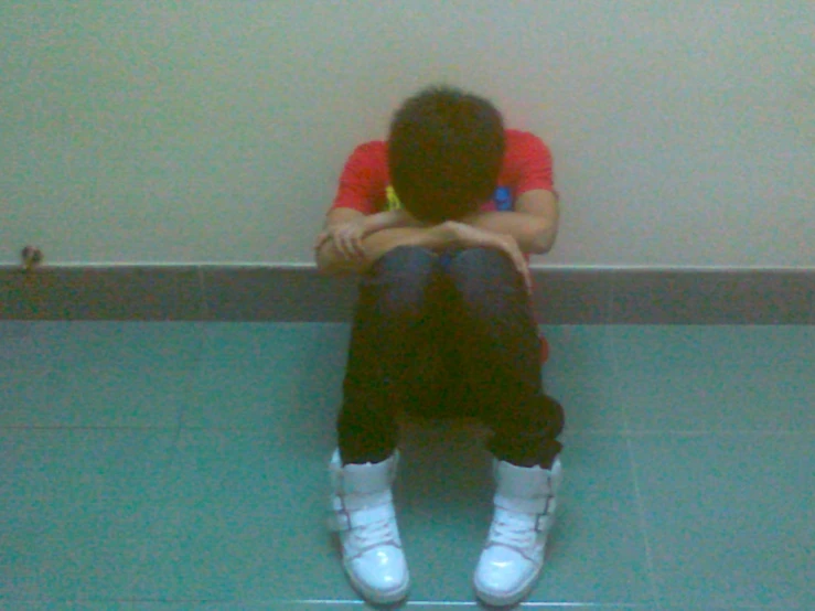 a person sitting on the ground with their head on his hands