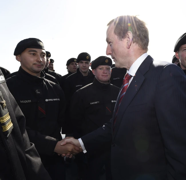 two men shaking hands with other men in uniform