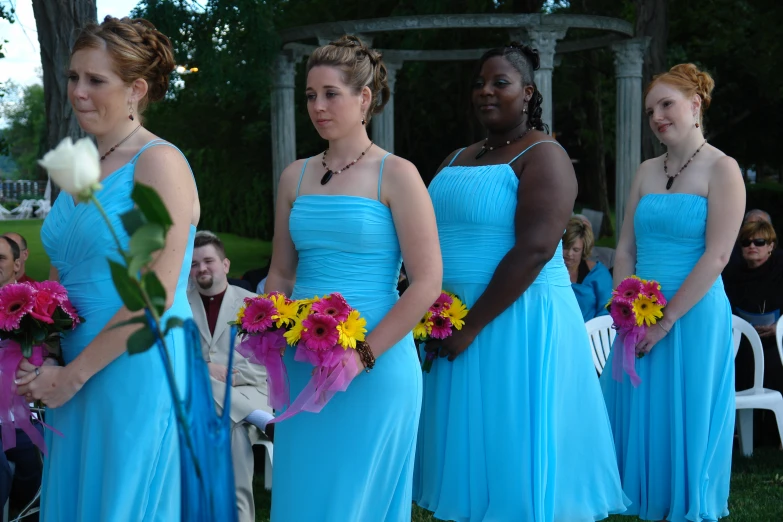 four women in blue dresses with flowers around their necks