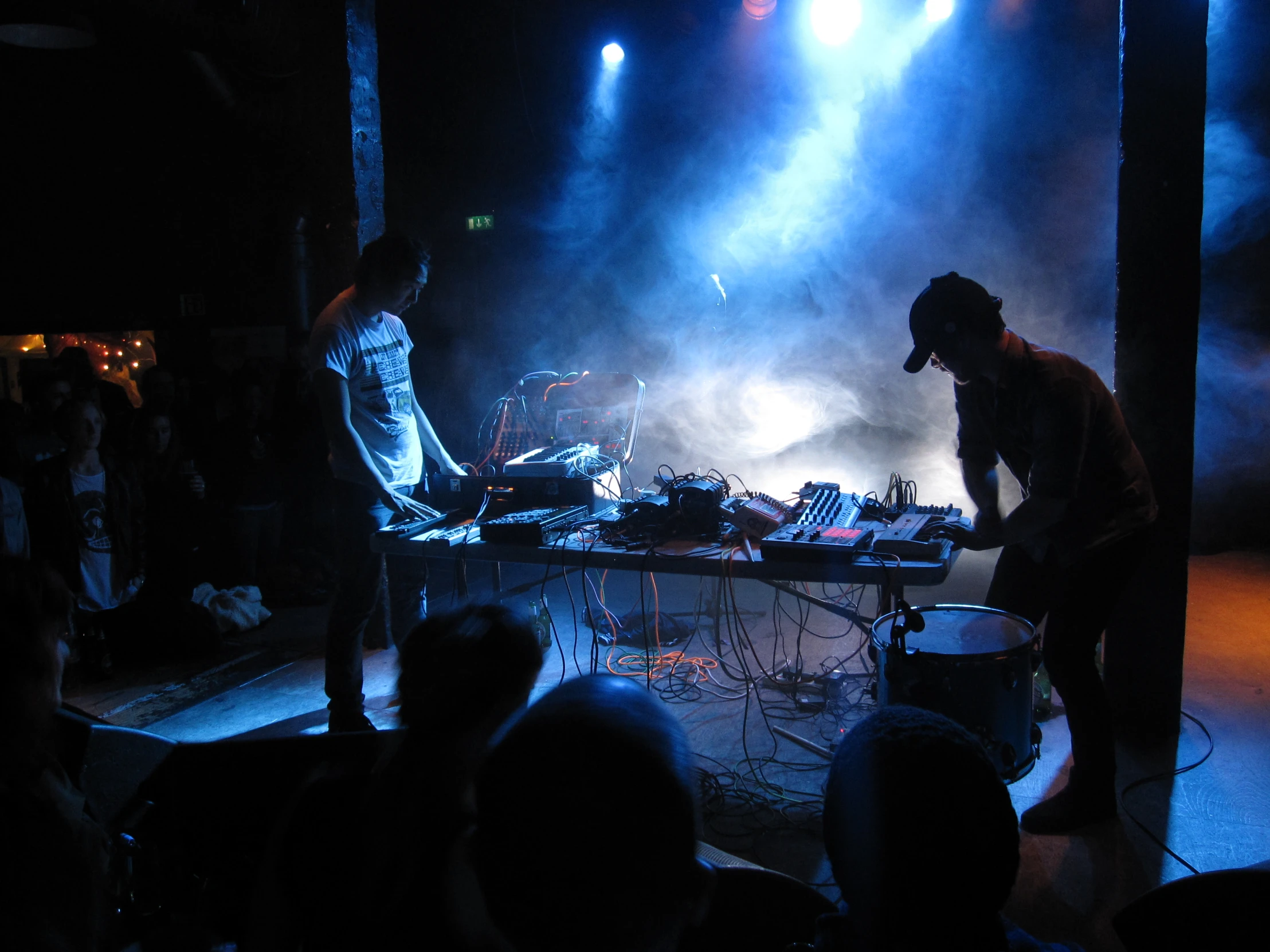 the man standing next to the man behind his dj's is playing music on stage