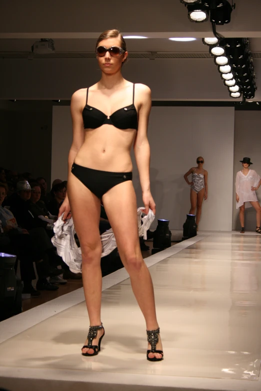 a woman is walking on a runway in a bikini