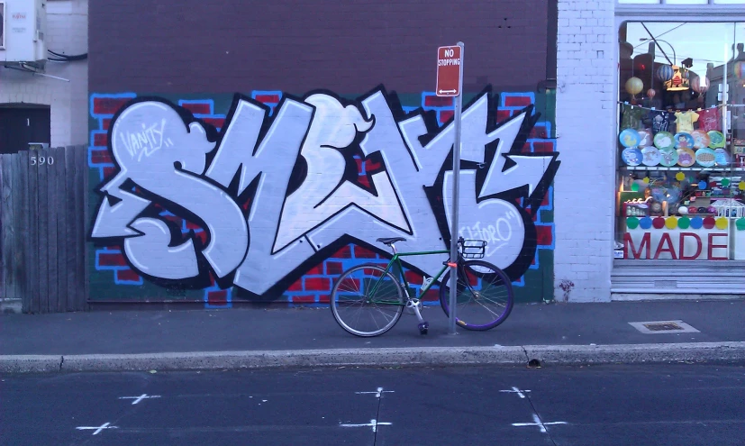 a bicycle parked next to a wall that has a graffiti covered side walk